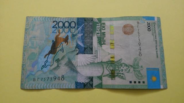 БАНКНОТА 2000 ТЕНГЕ № серии ВГ7573948 на жёлтой поверхности Двенадцатого Февраля - ДЕНЕЖНЫЙ ПОТОК смотреть онлайн
