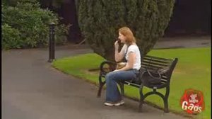 Boy peeing behind trash can outside.