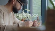 Modern man sits at the window in a cafe and writes in an organizer