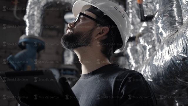 Technician engineer in a helmet works in a boiler room with a tablet смотреть онлайн