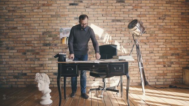 The man is standing near the table and scrolls through the notes