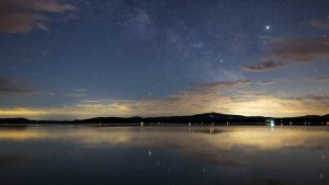 Ночное небо со звездами над спокойным озером, замедленная съемка