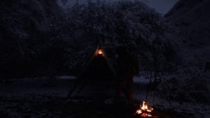 Одиночный зимний кемпинг в приподнятом убежище для выживания в лесу, приготовление пищи у костра