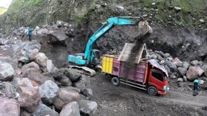 Строительство, экскаватор сбрасывает большой камень в шахту
