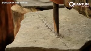 Мужчина строит дом из камней и дерева в лесу