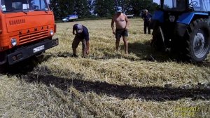 МТЗ 82 вытягивает гружёный КамАЗ с прицепом из болотного поля.