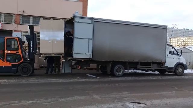 Грузоподъемник поднимает мебель в грузовик