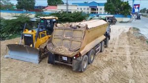 Бульдозер SHANUI и грузовик засыпают водоём.