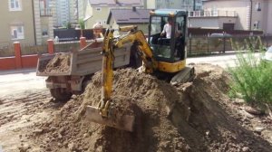 Аренда миниэкскаватора - погрузка грунта в самосвал.