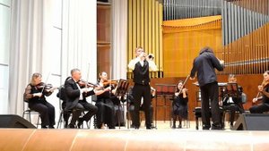 Юный музыкант играет на трубе со взрослым оркестром на большой сцене