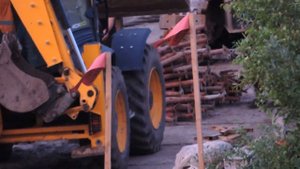Экскаватор погрузчик с вилами, вечером разгружает Грузовую машину.