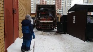 Рыжий мусоровоз загружает мусор