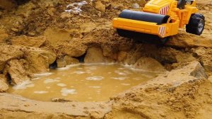 Трактор и экскаватор вытаскивает из реки игрушечные машинки. Дорожный каток застрял в грязи.