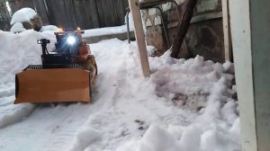 Бульдозер разгребает снег.
