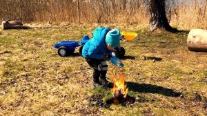 Мальчик катается на синем тракторе в парке.