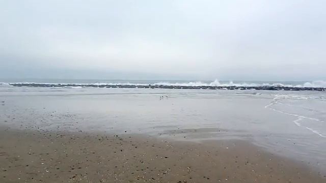 Волны, разбивающиеся о волнорез в корону из брызг...