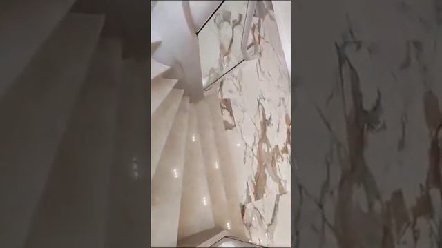 Лестница с забежными ступенями из камня и стеклянным ограждением