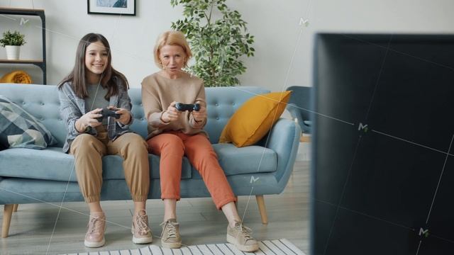 Joyful teenager playing video game with mature mother enjoying leisure time at home смотреть онлайн