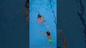 Дети в бассейне учатся плавать с маской и трубкой