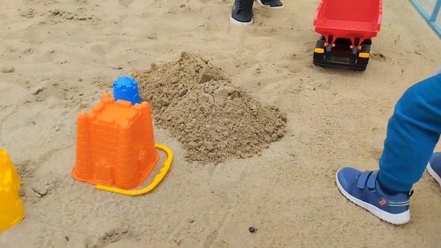Женя играет в большие машины и строит крепость из песк