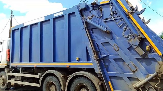 Мусоровоз МАЗ грузит мусор со склада магазина