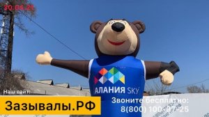 Надувной мишка машет рукой