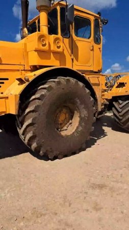 Большой трактор едет по полю