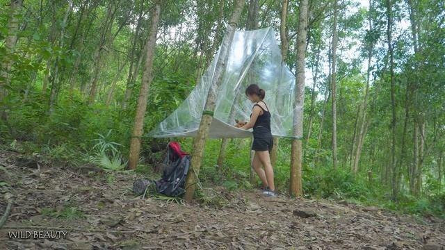 Девушка строит укрытие из пленки в лесу