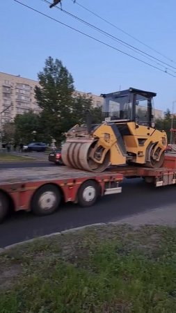 Грузовик везет каток для асвальта на трале