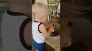 Малыш моет посуду.