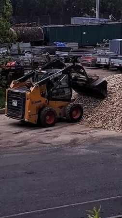 Погрузчик возит щебенку в ковше