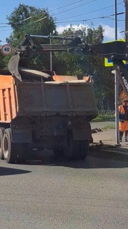 Экскаватор загружает бардюры в грузовик самосвал