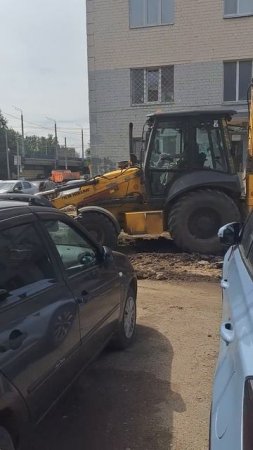 Экскаватор работает во дворе убирает старый асфальт