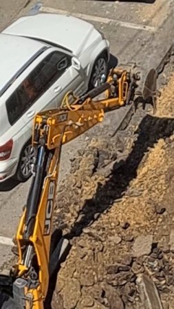 Трактор экскаватор ломает асфальт