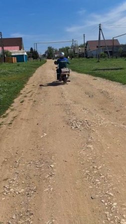 Байкер в серебристом шлеме едет по деревенской дороге