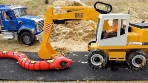 Бибо играет в песке с игрушечным грузовичком-экскаватором