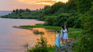Три девушки на фотосессии у реки на закате дня