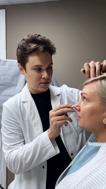 пластический хирург делает разметку на лице пациентки перед операцией в клинике