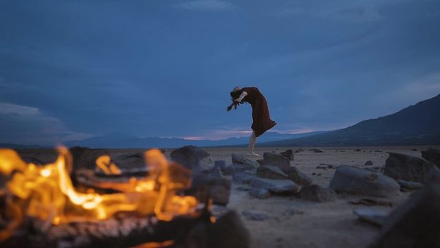 Пустынная равнина с костром и женщиной, практикующей йогу