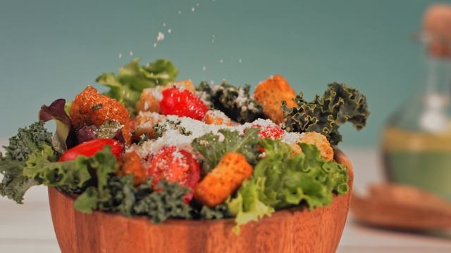 Сыр пармезан, посыпанный в замедленной съемке на вкусный зеленый салат
