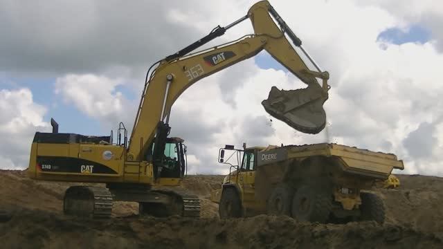 Экскаватор Cat 374D LME грузит самосвалы John Deere 400D смотреть онлайн