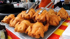 Жареный цыпленок в котле на уличном рынке. Корейская уличная еда