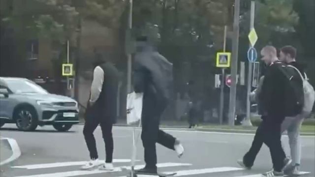 Парень со сломанной ногой пересекает дорогу на скейте удерживая равновесие с помощью костылей