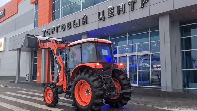Японский трактор Kubota M704-KQ с кабиной  и КУНом едет по парковке ТЦ Dexter 1