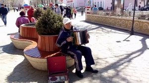 Он играет на старой гармошке