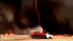 Пожарные тушат траву, не смотря на находяшийся рядом огненный смерч