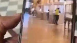 Видео ограбления в Лувре: мужчина в капюшоне и жёлтом жилете вскрывает витрину в галерее Аполлона.