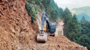 Экскаватор строит дорогу на краю обрыва.