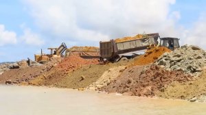 Много грузовиков и бульдозеров засыпают гектар камнями.