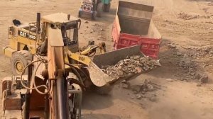 Caterpillar 966 загружает массивные камни в грузовик.